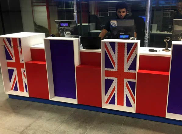 A colourful reception desk at a tourist attraction, finished in red, blue and white with large Union Flag decorated panels
